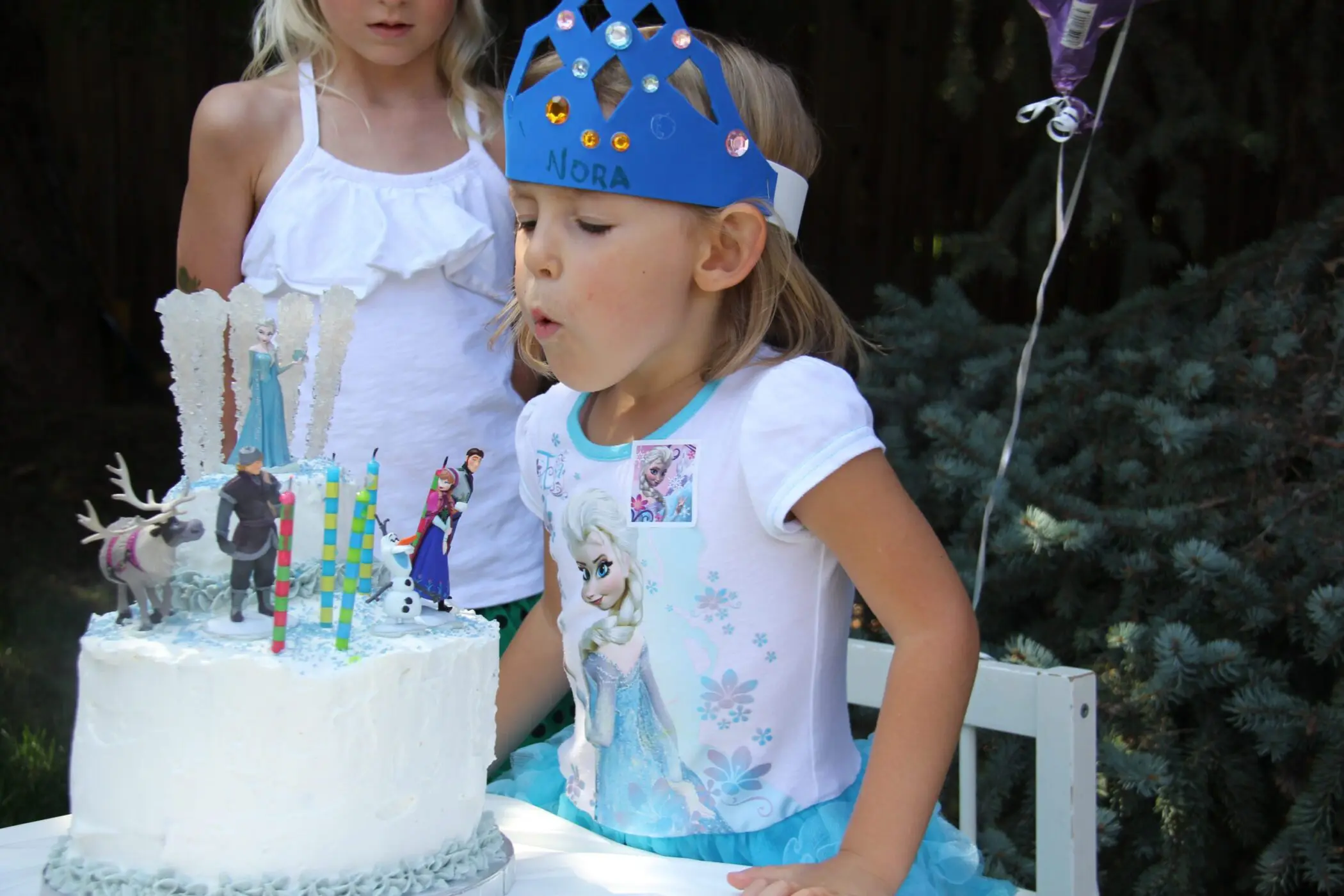 Nora blowing out candles on her Frozen cake
