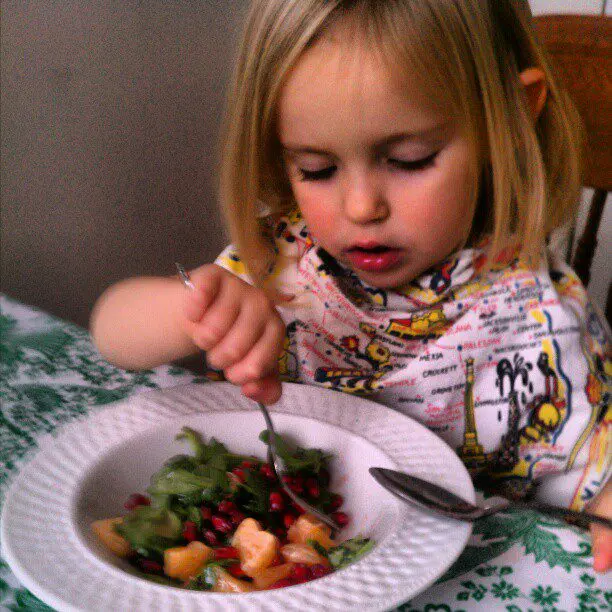 Nora eats salad with both hands.