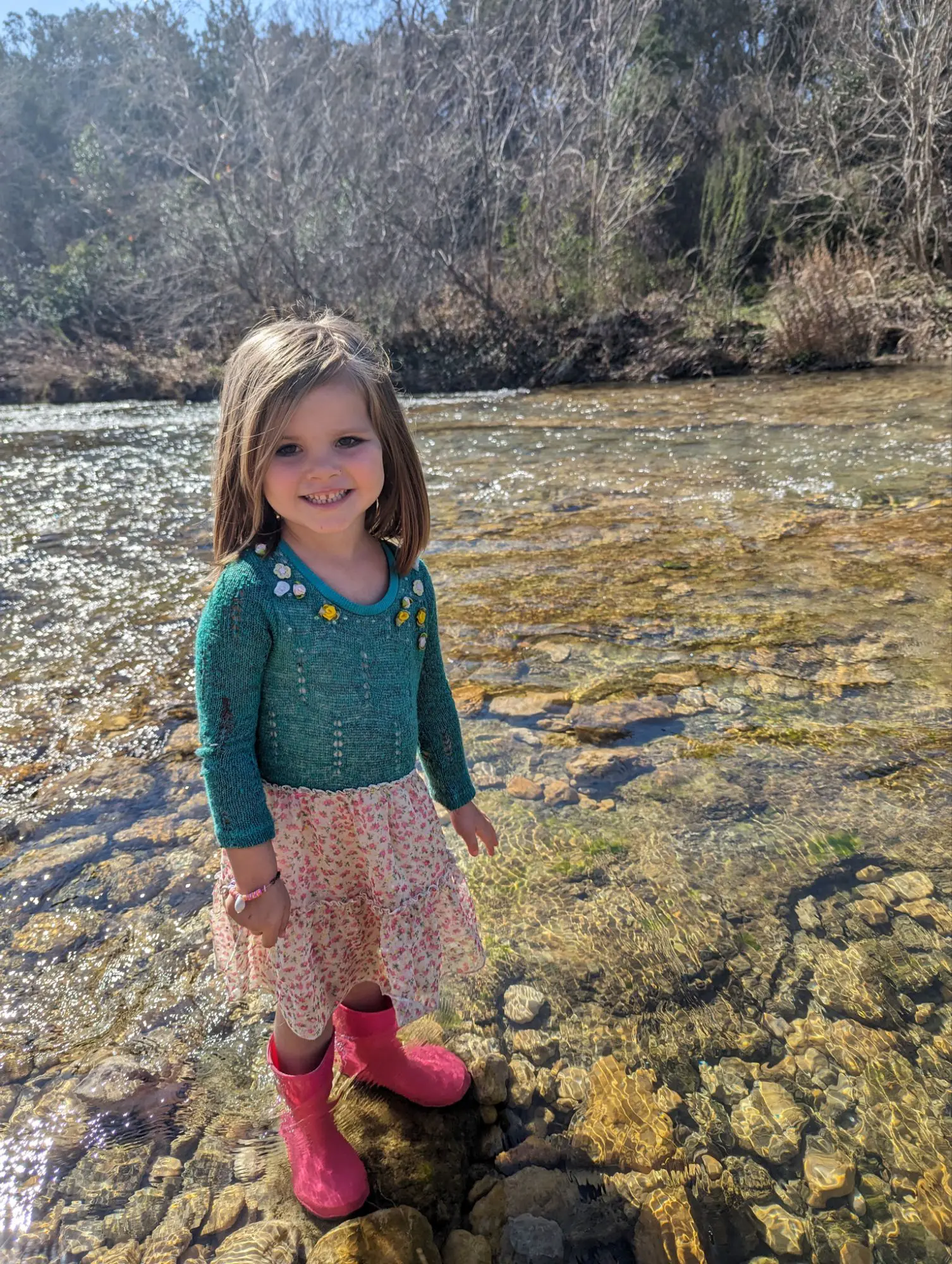 Vivienne standing in the river wearing rainboots.
