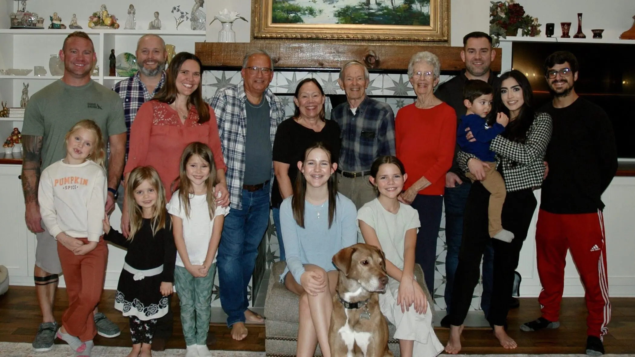 A large group photo of Amber's family and extended family (10 adults and 6 children) standing in front of a fireplace with a dog sitting in front.