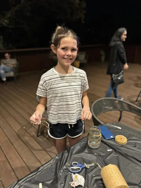 Zara decorating a mason jar to make a lantern.