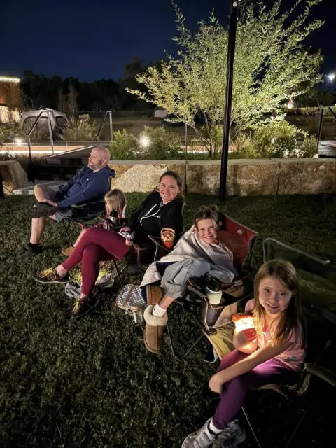 The Hinds family (minus Nora) sitting in camping chairs outside at night.