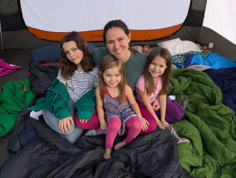 Amber, Zara, Addie, and Vivi sitting on sleeping bags in a tent.