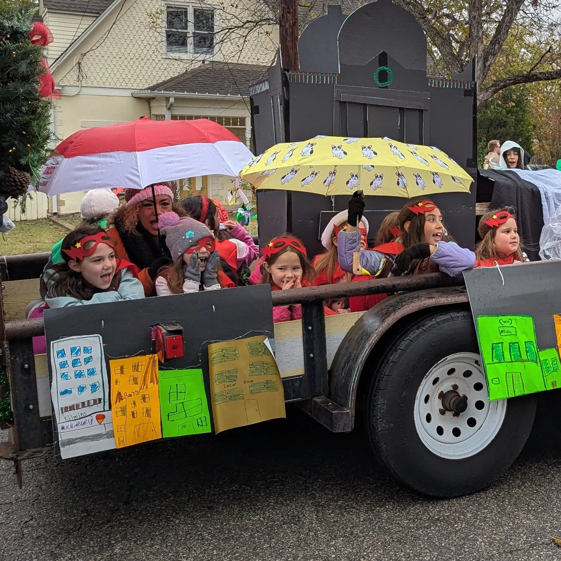 Addie giggling as she rides on the girl scout float which is super hero themed.