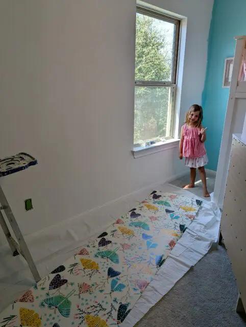 Vivi standing next to an unrolled roll of wallpaper giving a thumbs up.