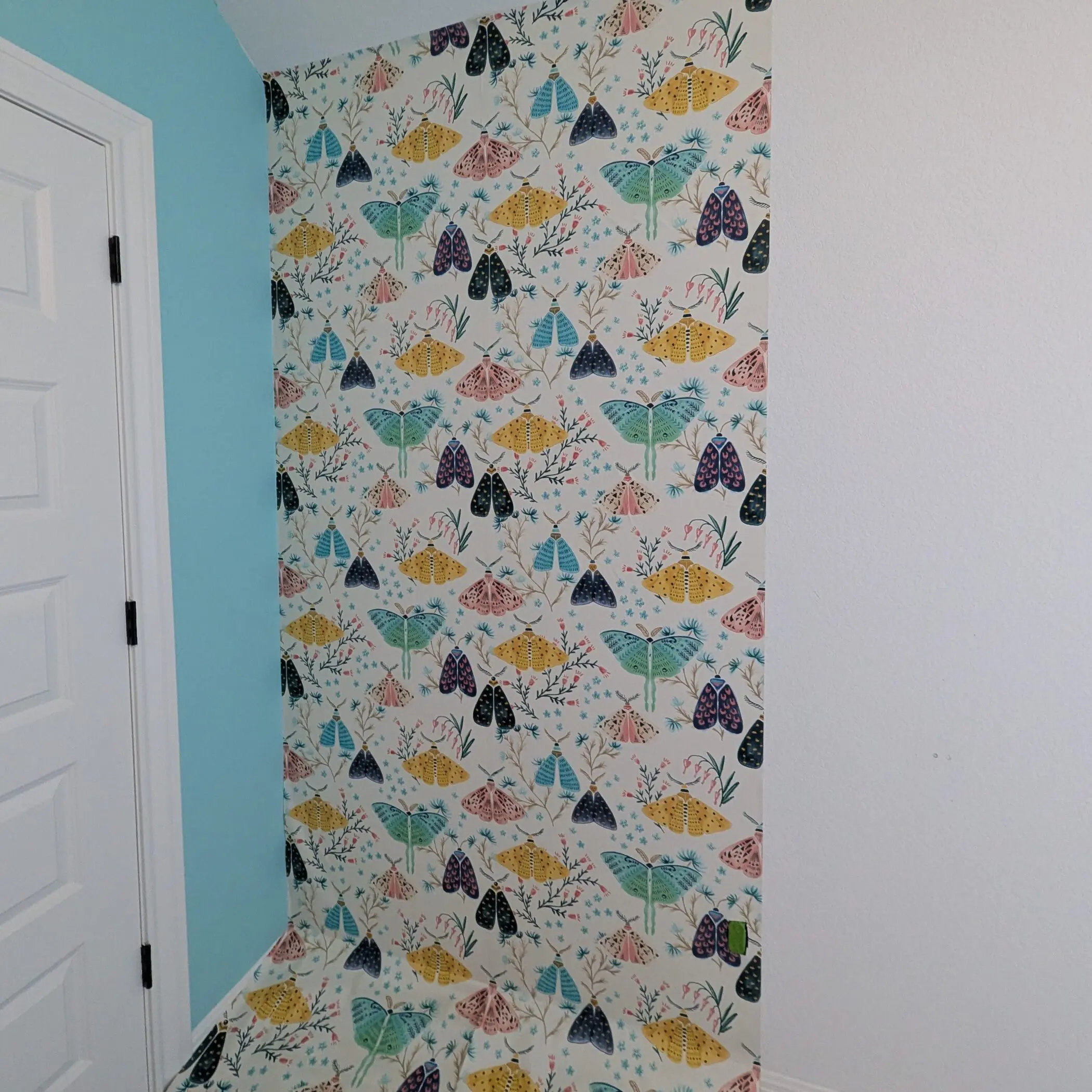 In-progress with two strips of wallpaper hung on the wall.