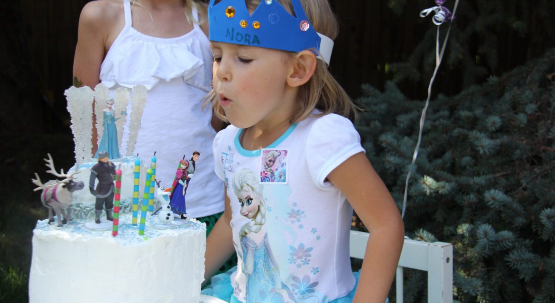 Nora blowing out candles on her Frozen cake