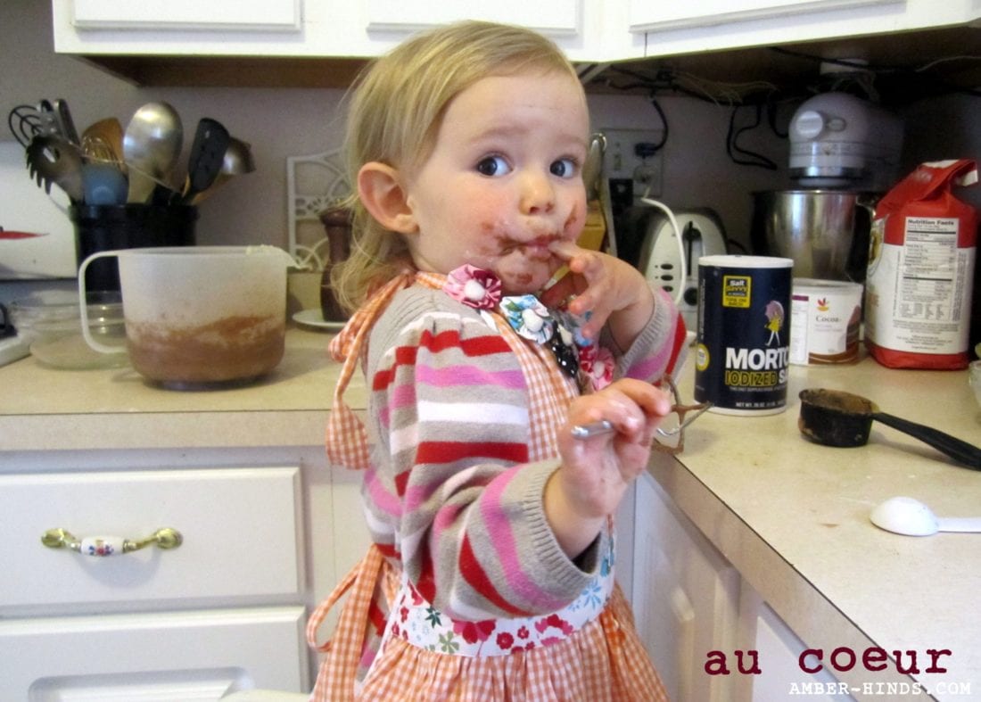 toddler Nora baking with a messy face