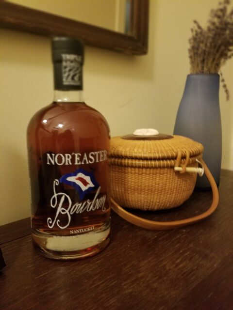 Bottle of Nor'Easter Bourbon from Nantucket sitting next to Amber's Nantucket lightship basket purse.