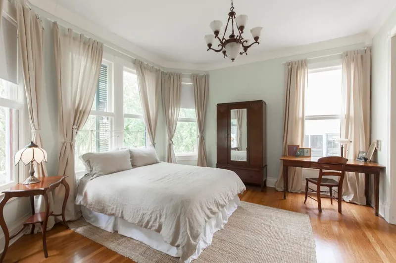 The elegant bedroom with 5 nearly floor to ceiling windows and antique furniture.
