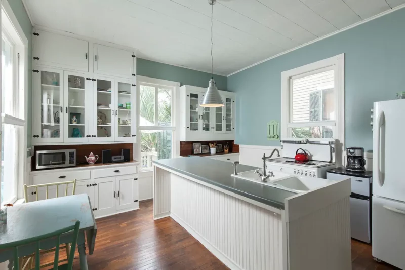 The kitchen has original built-in cabinets with glass fronts and a gas stove from the 40s.