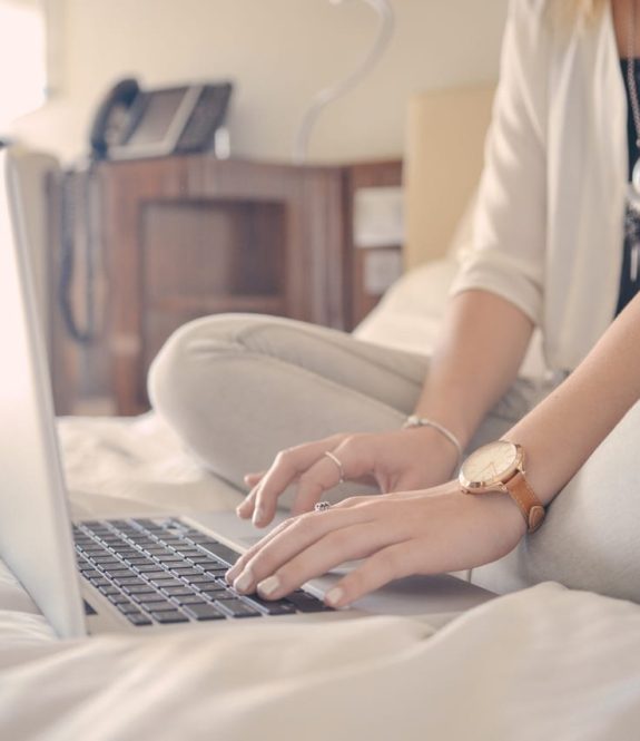 woman typing on computer on bed