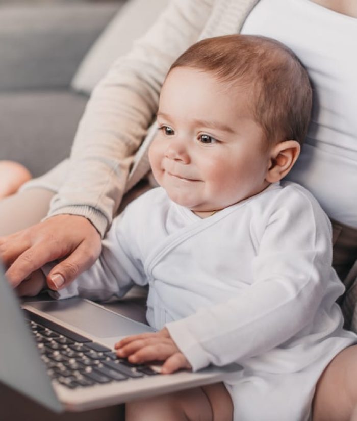 baby sitting on mom's lap looking at computer
